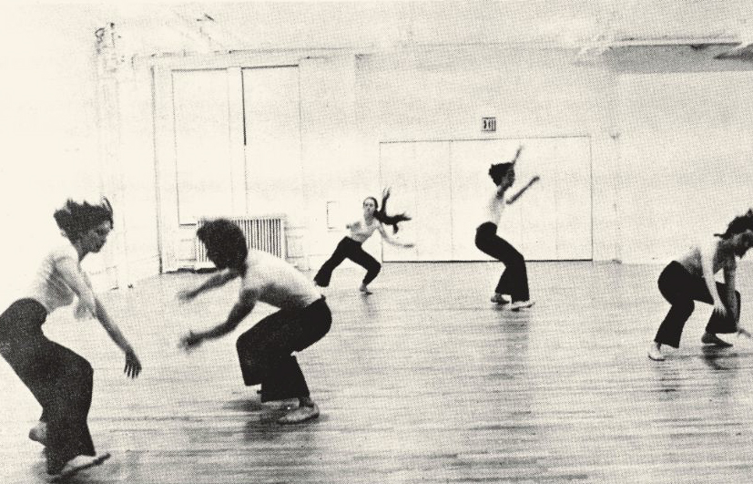 Dancers in a studio captured mid-movement, bodies crouching and leaping in expressive poses